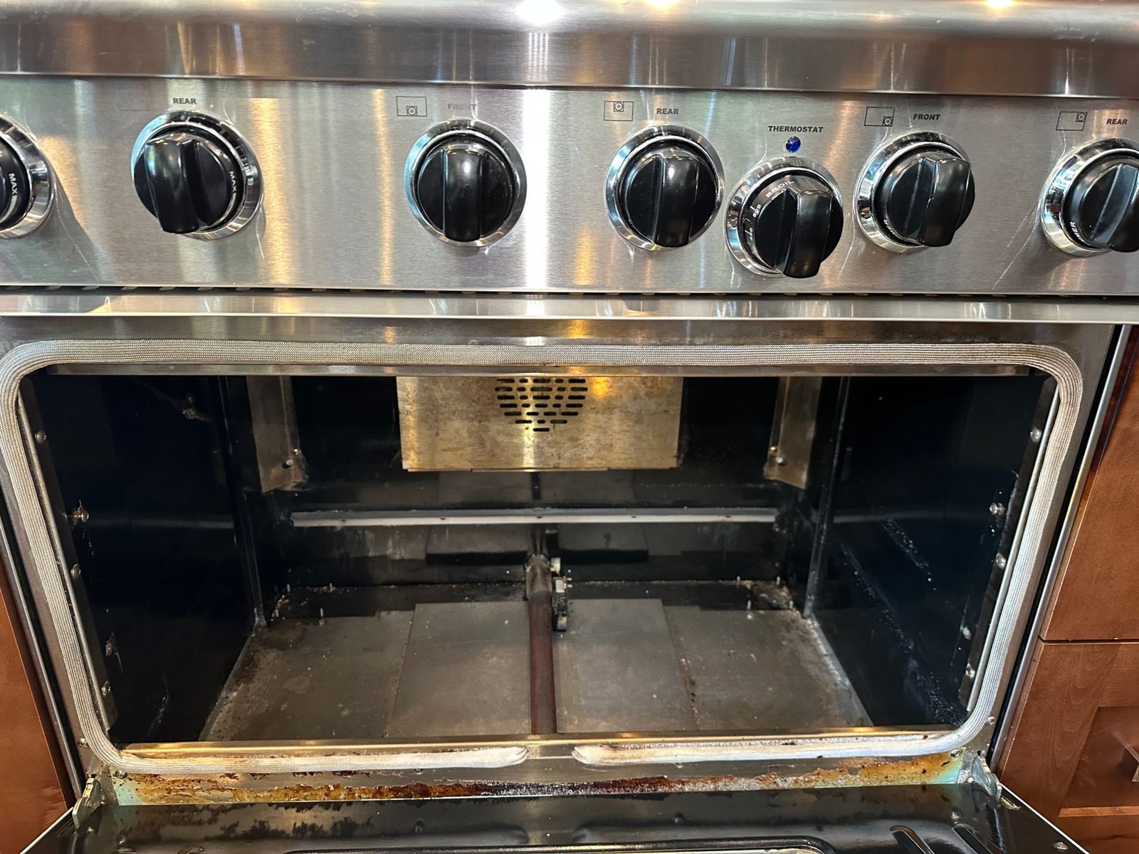 American Range oven open with the floor panel removed, exposing the bake burner