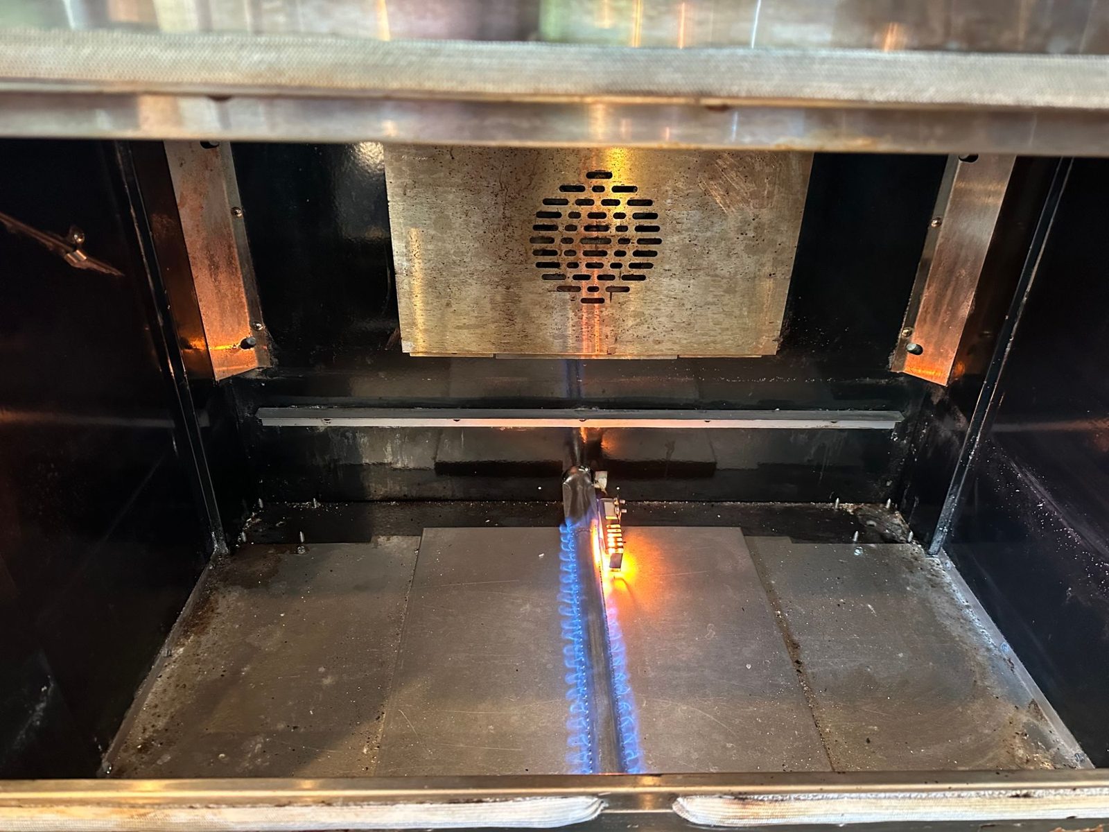 New American Range bake burner lit with a steady blue flame and the igniter glowing orange