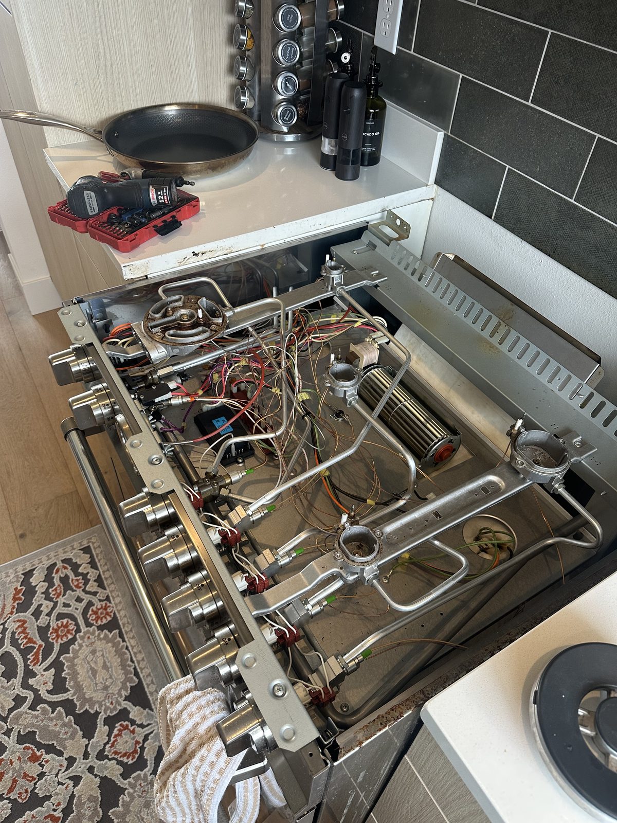 Bertazzoni range with control panel open, burner valves and wiring exposed for repair