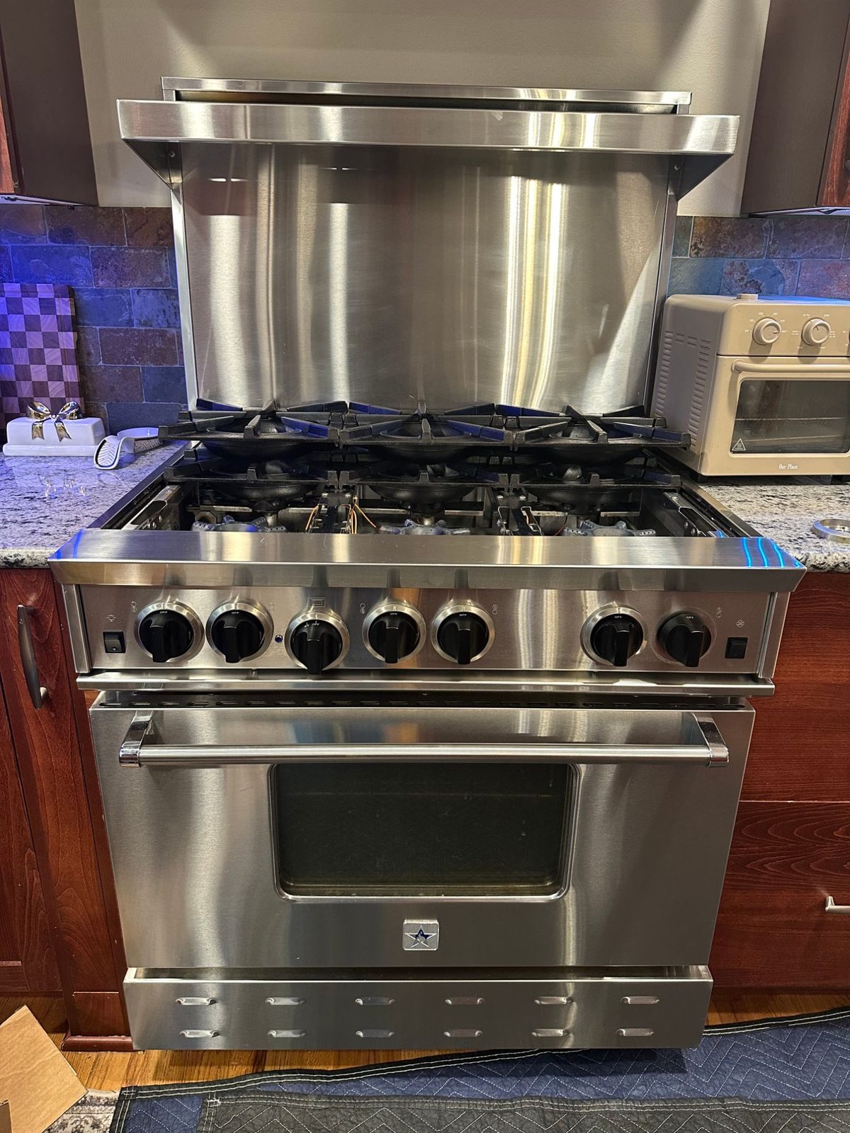 BlueStar 36-inch RNB366BSS stainless range with the cast-iron grates lifted and the six open burners exposed