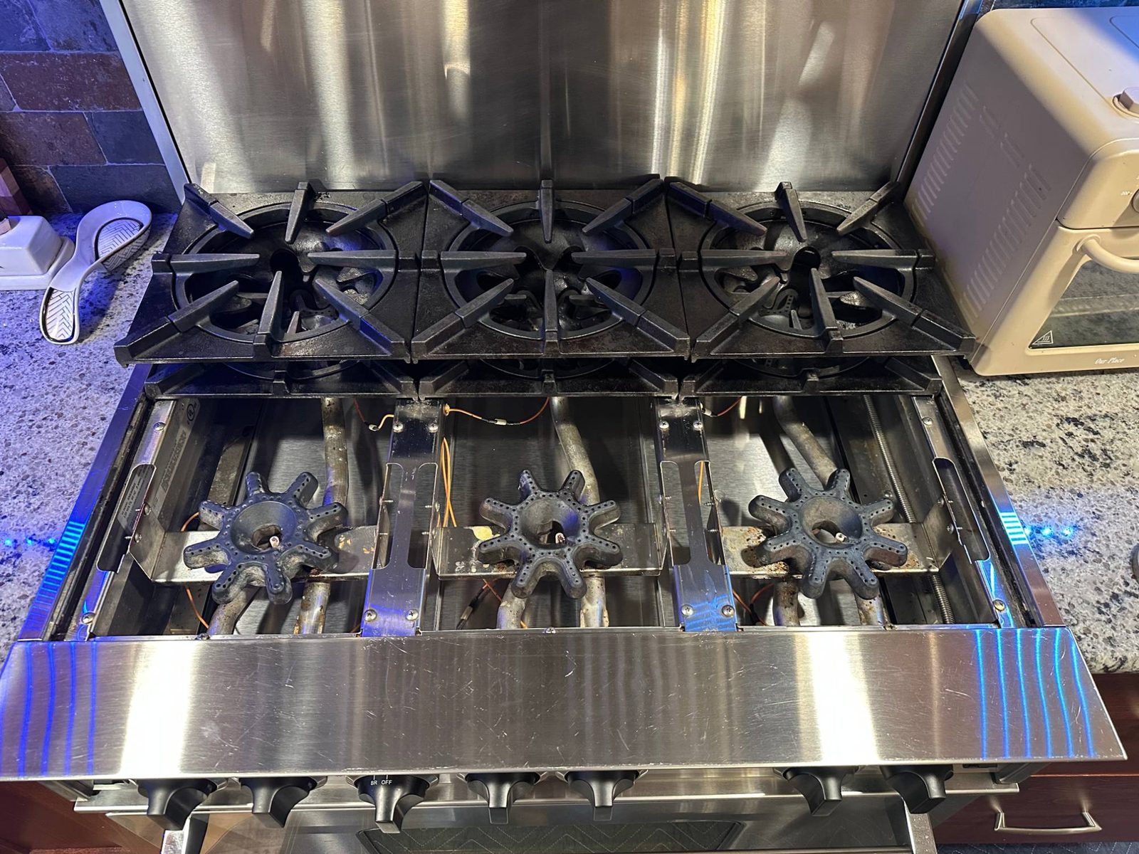 Top-down view of three BlueStar star-shaped open burners with the igniter wires running between them