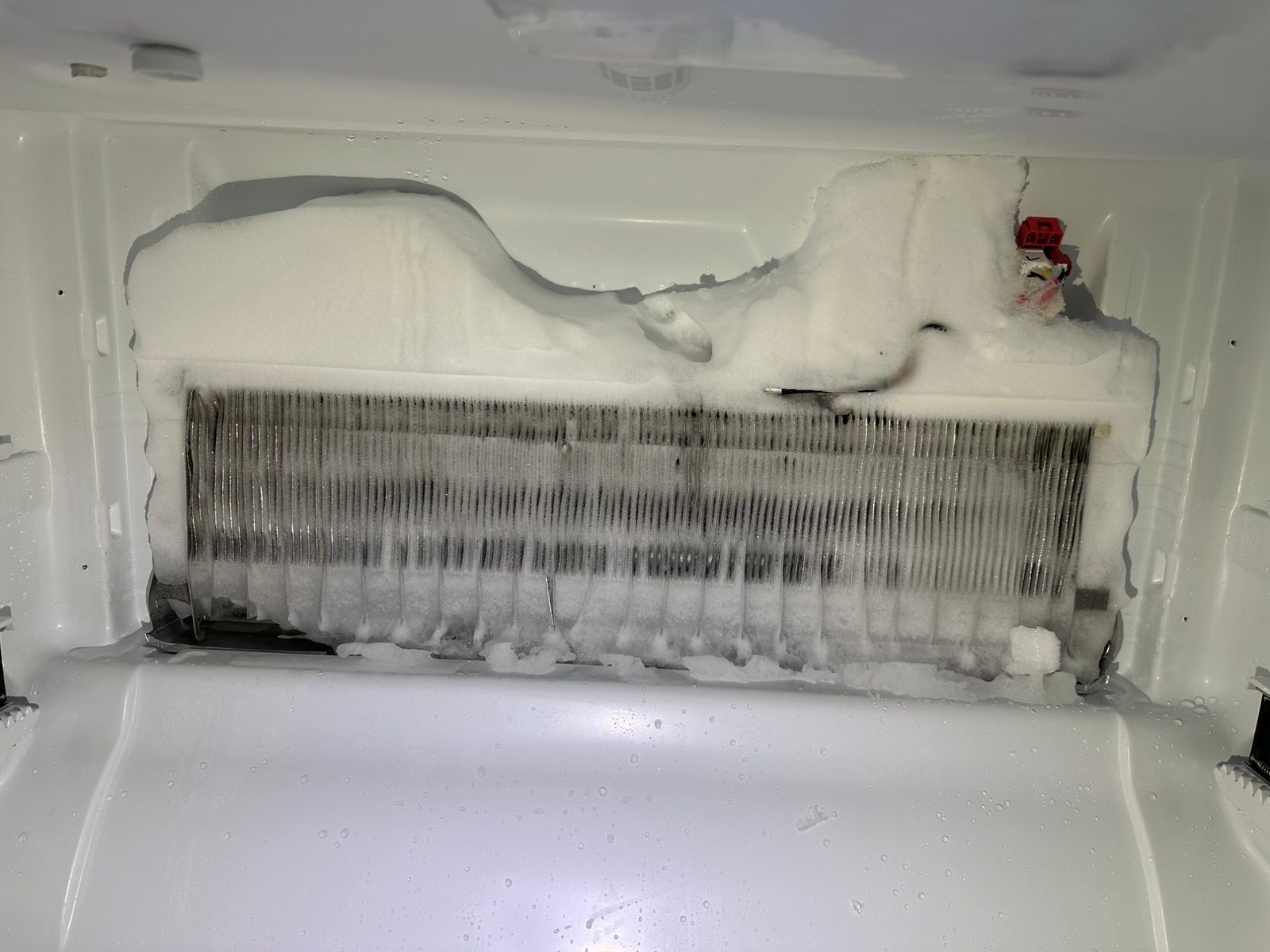 Close-up of the iced-over Bosch evaporator coil, with frost built up over the top and between the fins