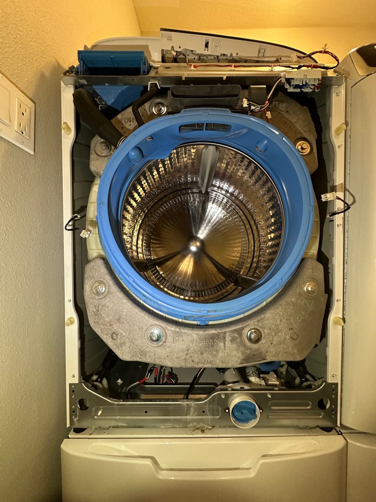 GE front-load washer with the front panel and door removed, showing the tub, drum and front counterweight