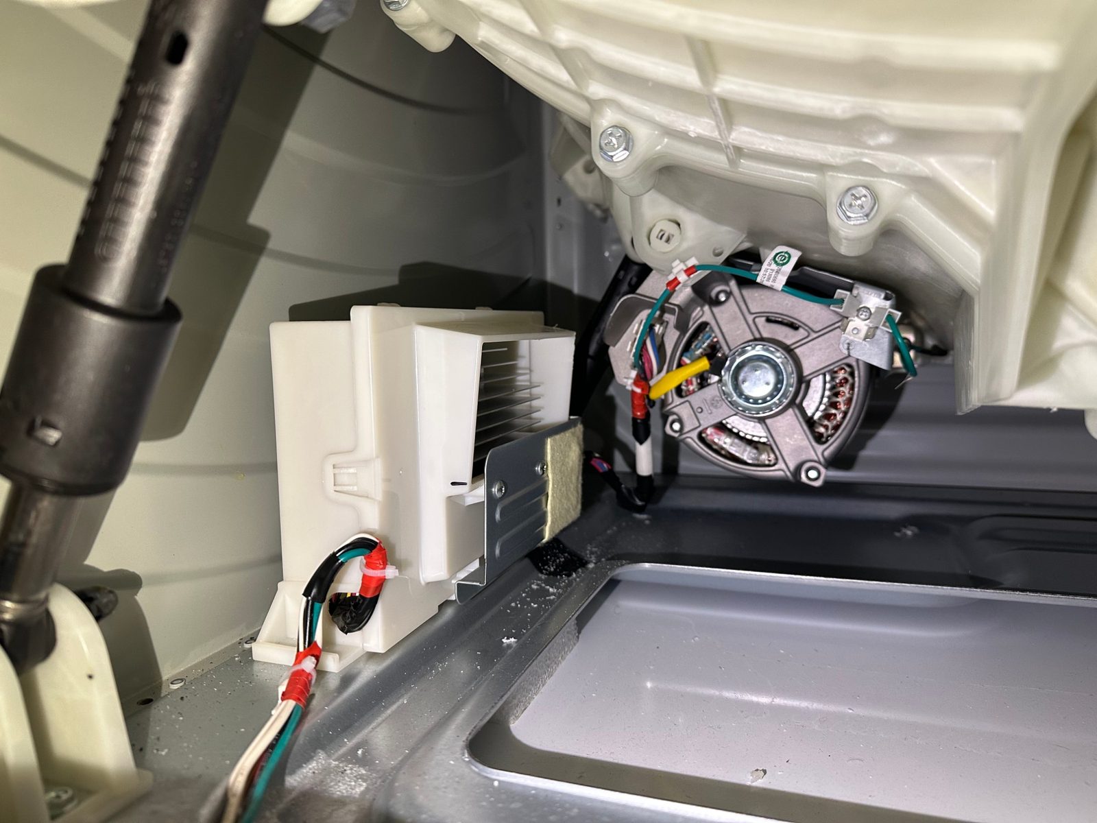 GE washer inverter board in its white plastic housing at the base of the cabinet, next to the direct-drive motor