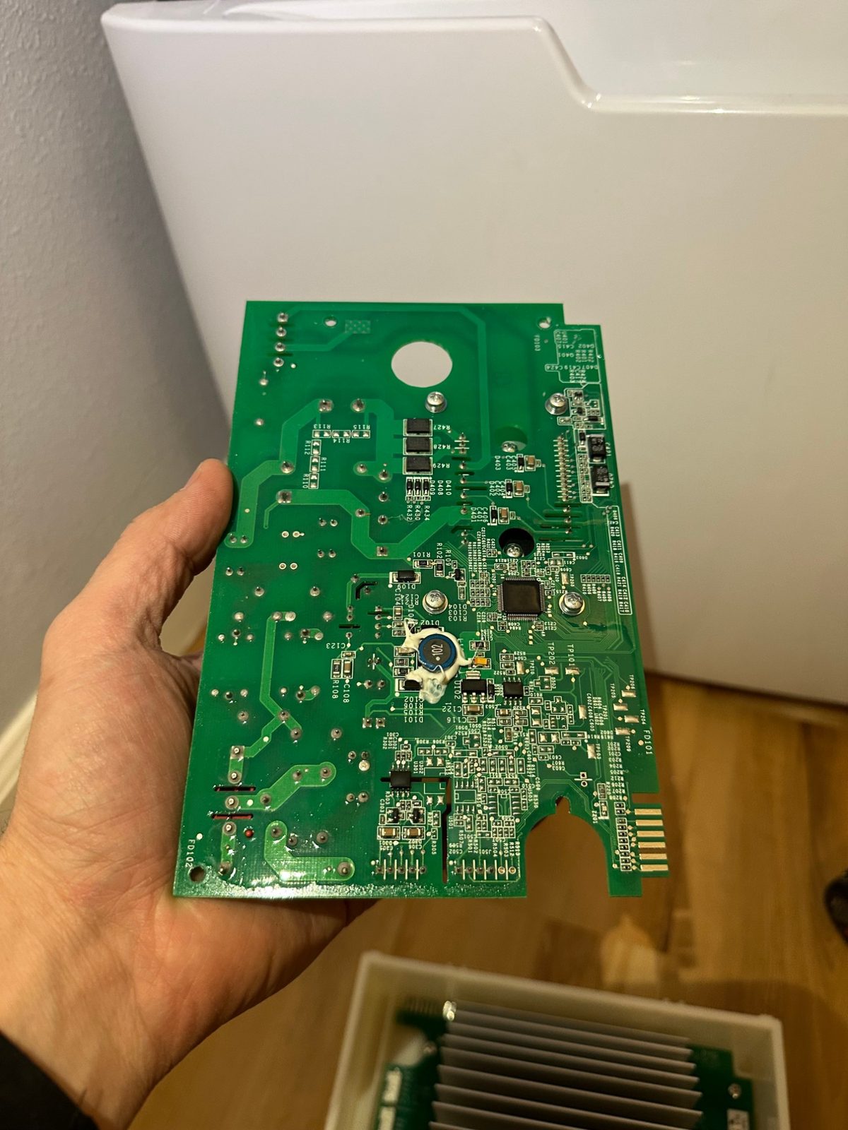 Underside of a GE washer inverter circuit board held in a hand, showing traces and surface-mount components