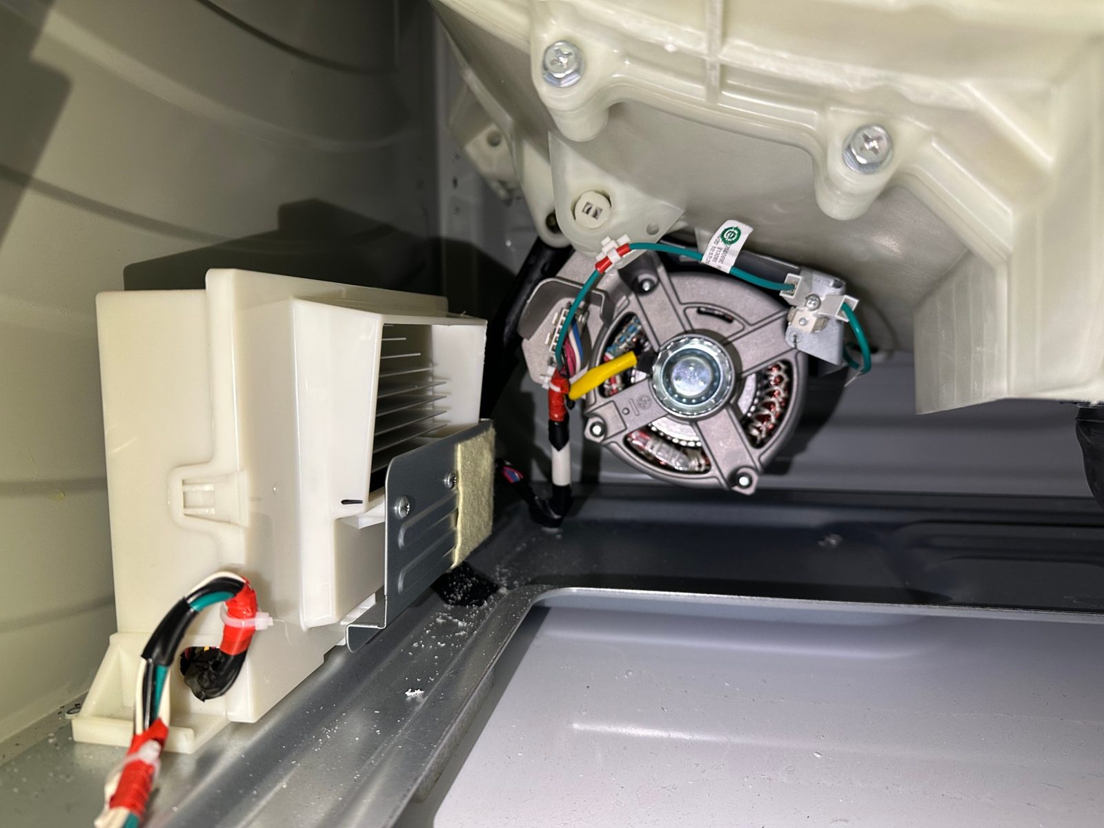 New GE inverter board in its housing reinstalled at the base of the washer with the wiring harness connected