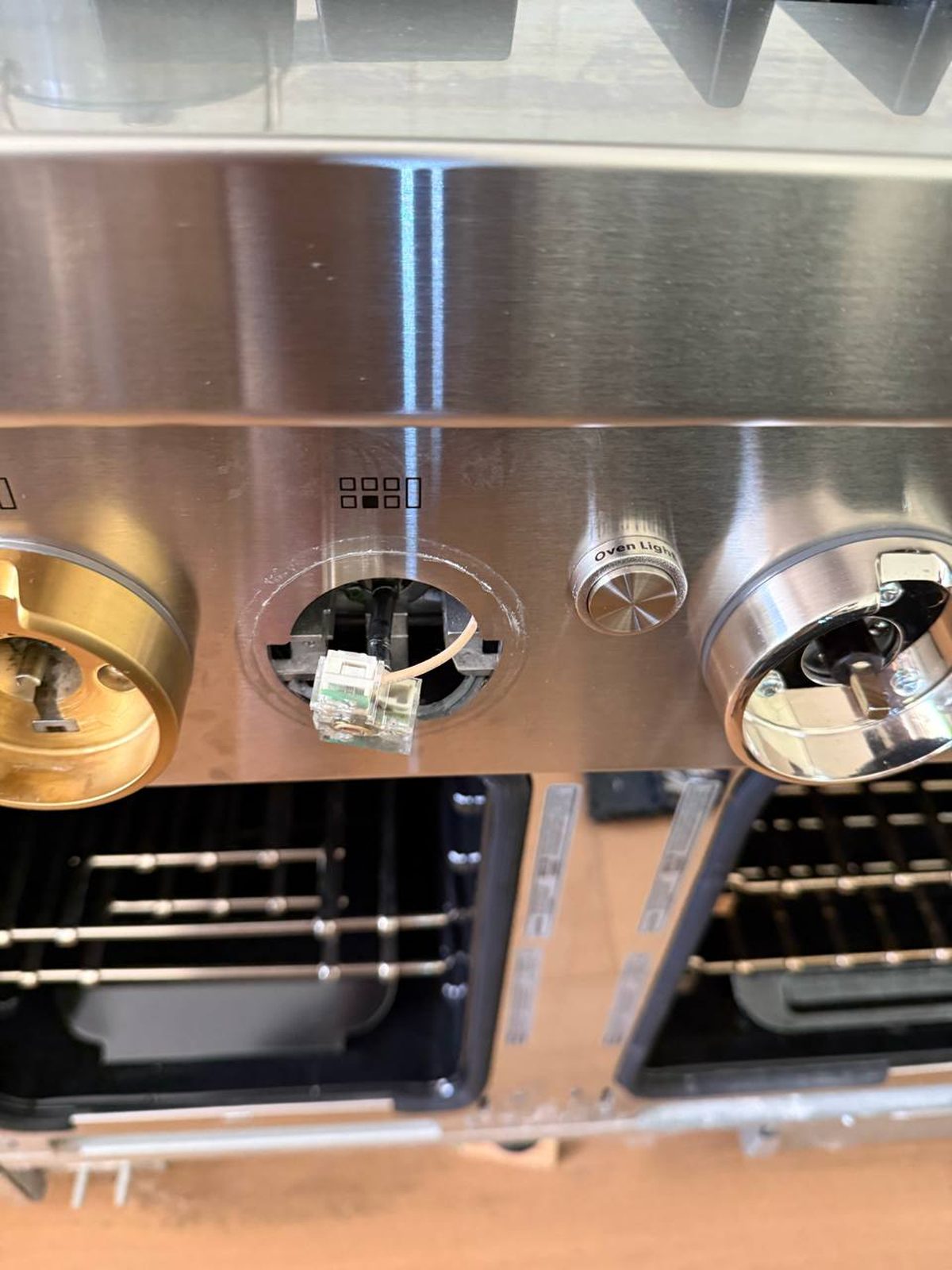Jenn-Air control panel with a knob removed, reconnecting the switch behind it during reassembly