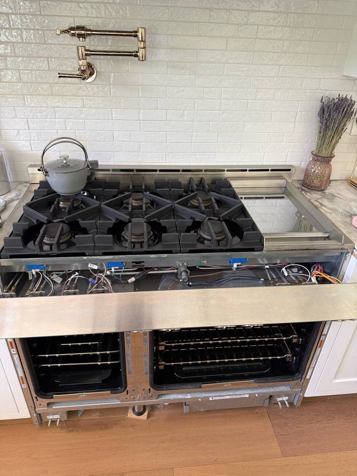 Jenn-Air range with cooktop panel raised to access the gas valve manifold and igniter wiring