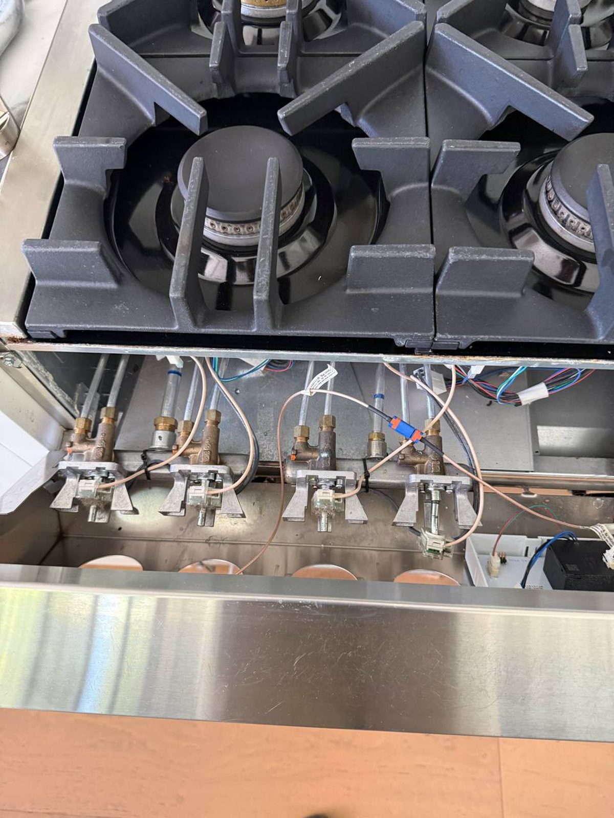 Close-up of the four gas valve assemblies on the Jenn-Air range, with the failed valve's wiring reconnected