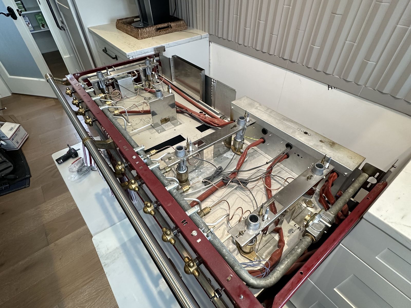 Lacanche range with cooktop removed, gas valve manifold and wiring exposed for repair