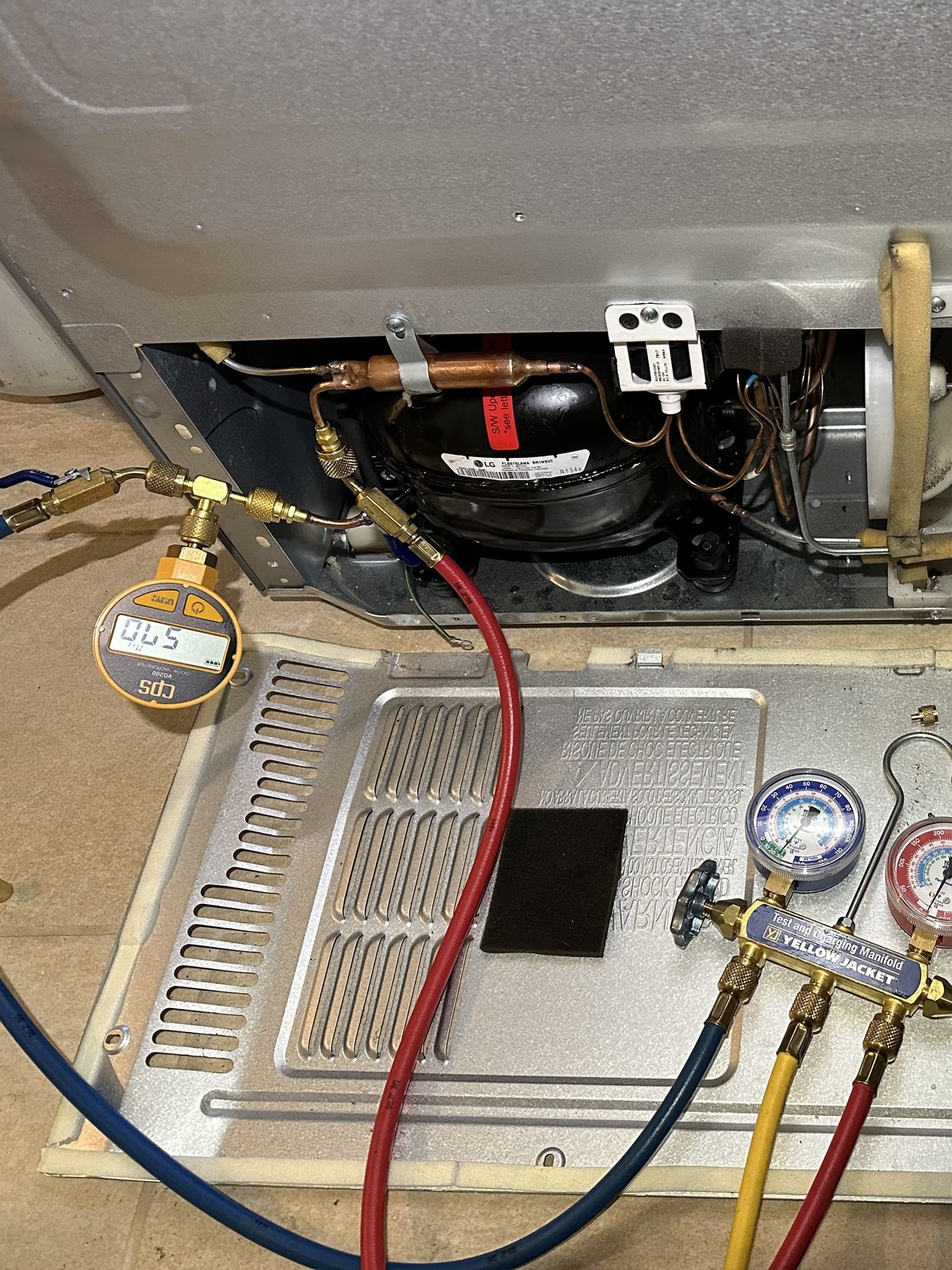 LG refrigerator compressor compartment open for compressor replacement, with refrigerant gauges attached