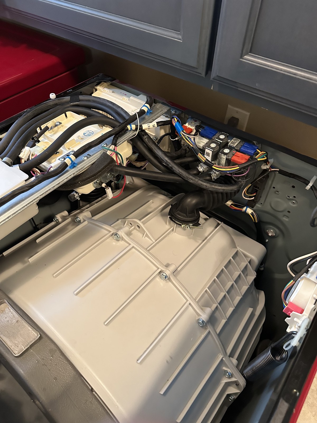 LG washer with the top panel open, exposing the water inlet valve and wiring harness