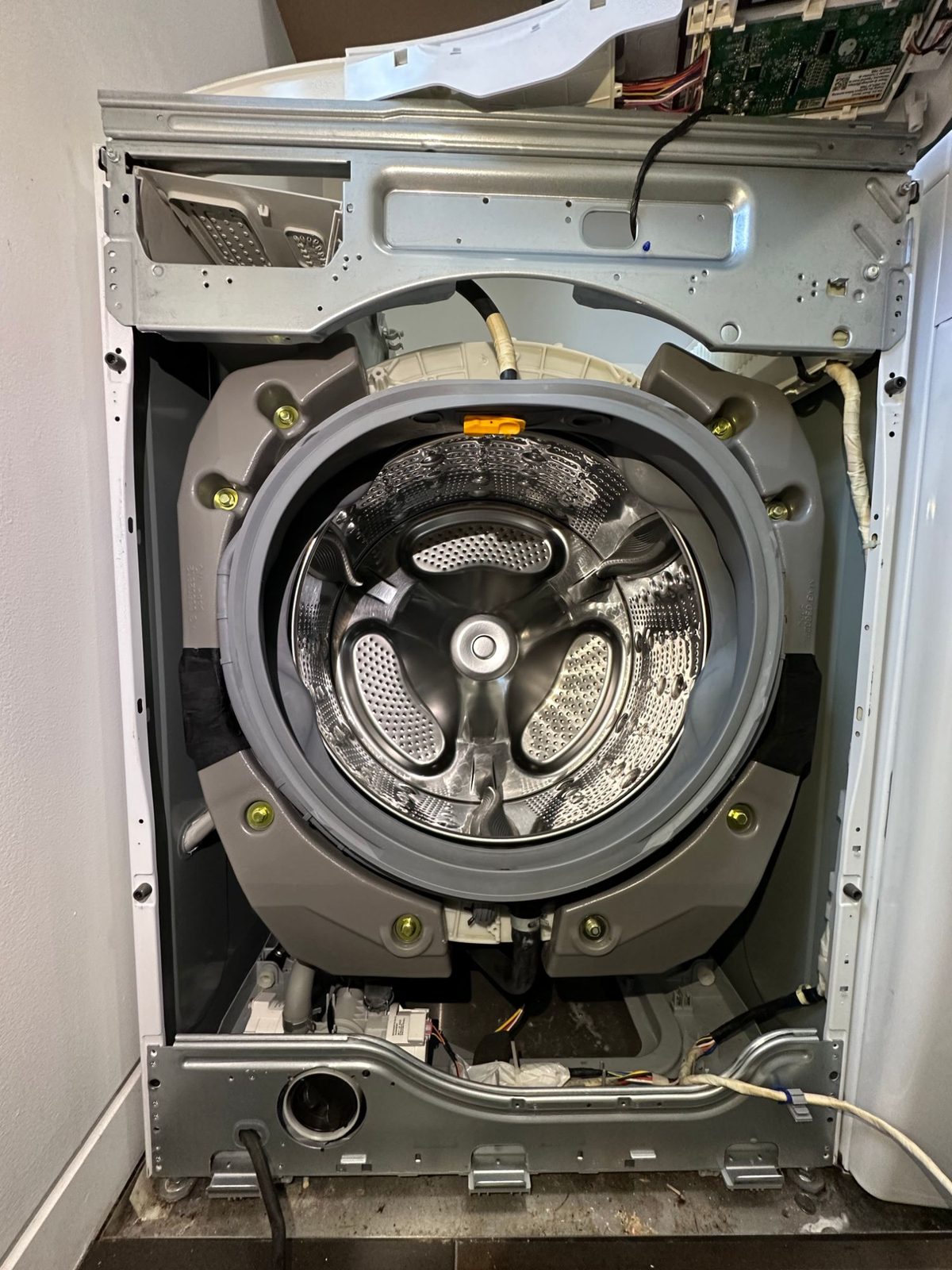 LG front-load washer with the front panel still off and the new clean gray door boot gasket installed on the tub