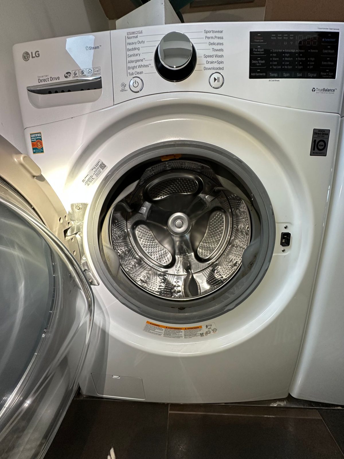 White LG front-load washer with the door open, showing the gray door boot gasket around the drum opening before the repair