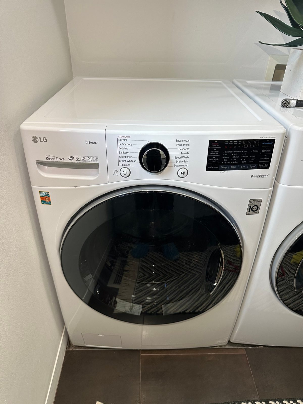LG front-load washer fully reassembled with the door closed in a laundry room