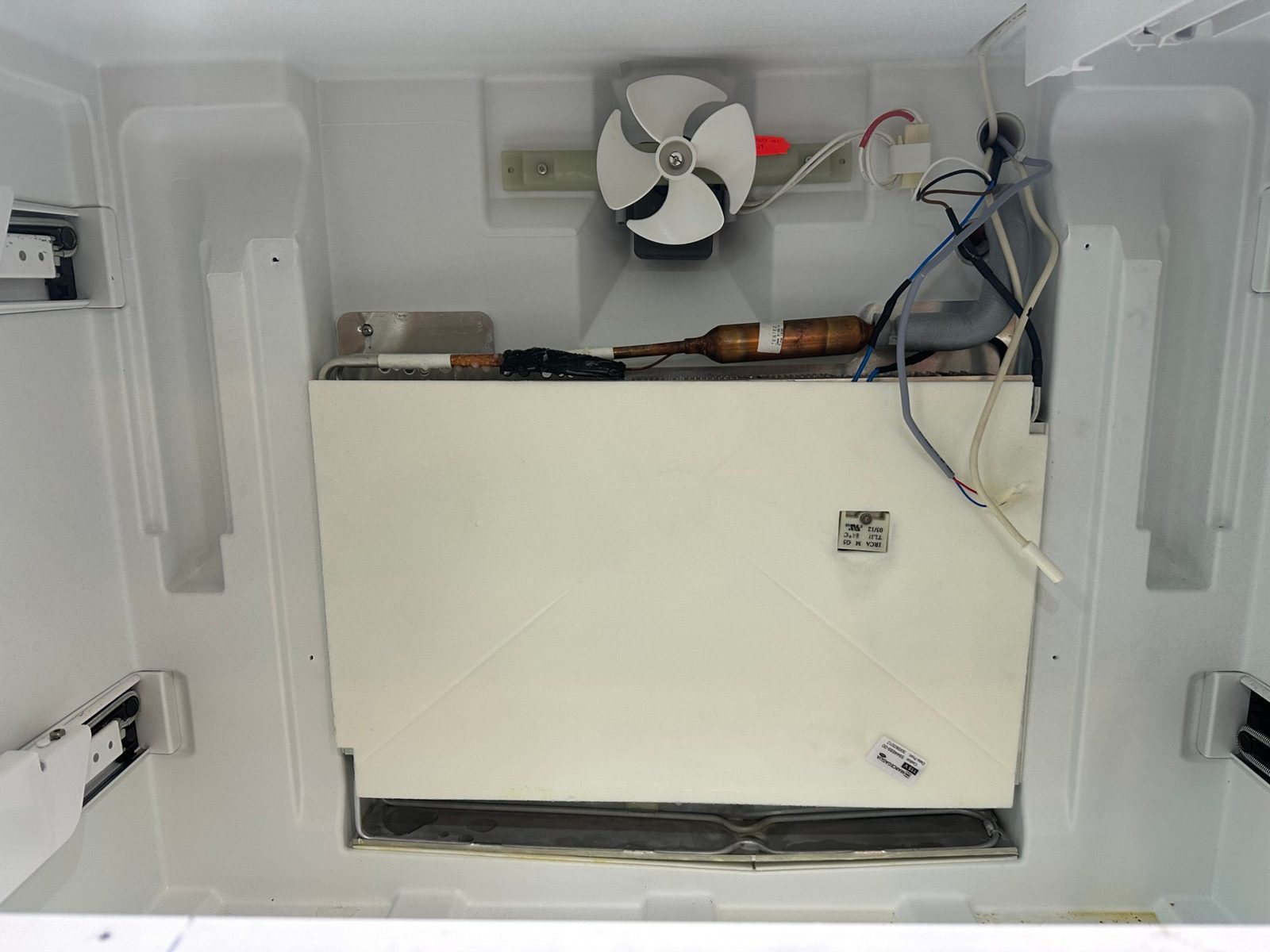 Liebherr freezer compartment with the rear cover removed, showing the evaporator cover, fan, and refrigerant lines