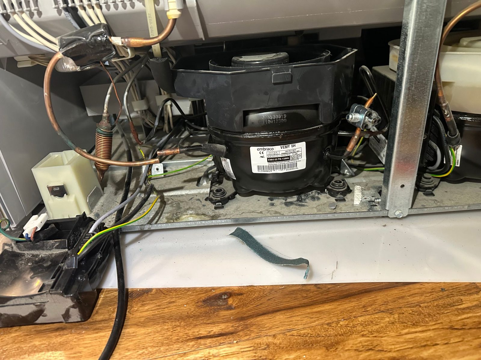 Original Embraco compressor in the Liebherr machine compartment with the refrigerant lines cut and the electrical box disconnected
