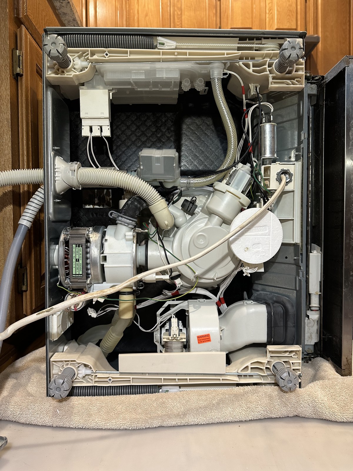 Miele dishwasher with the outer shell removed, exposing the wash pump, motor, and spray arm assembly