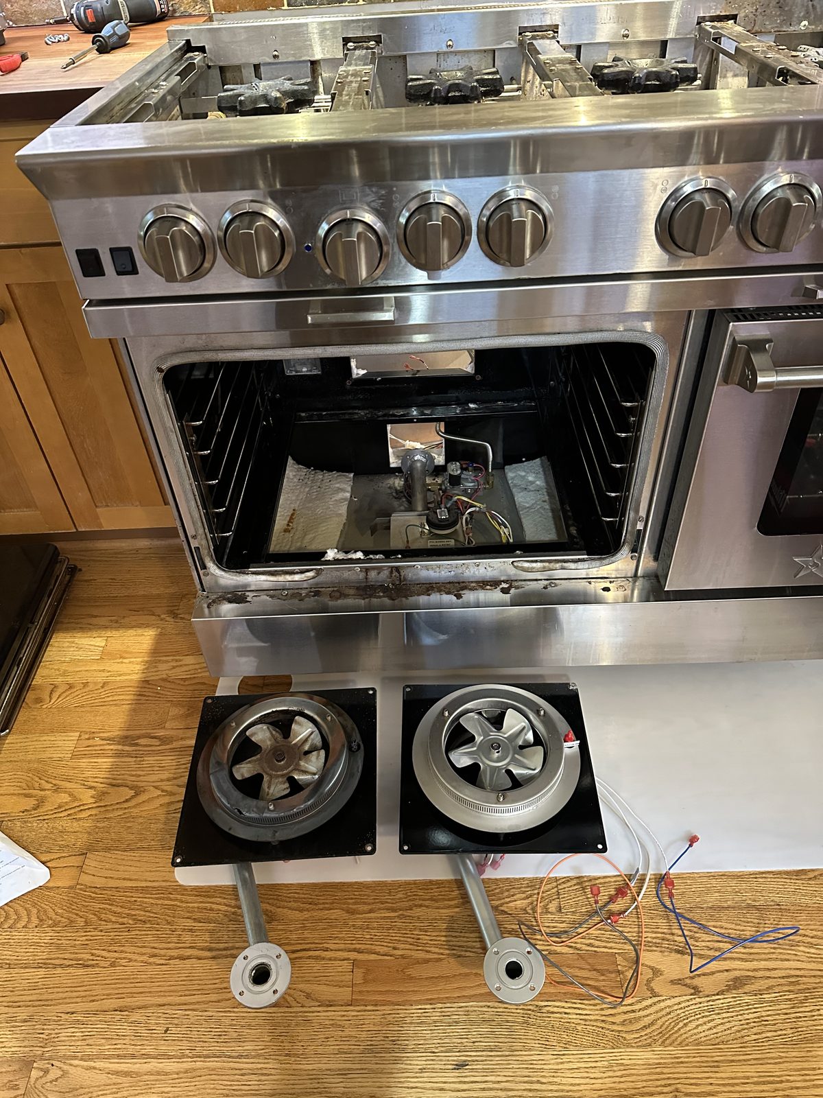 Range hood blower fans removed for service alongside oven igniter repair