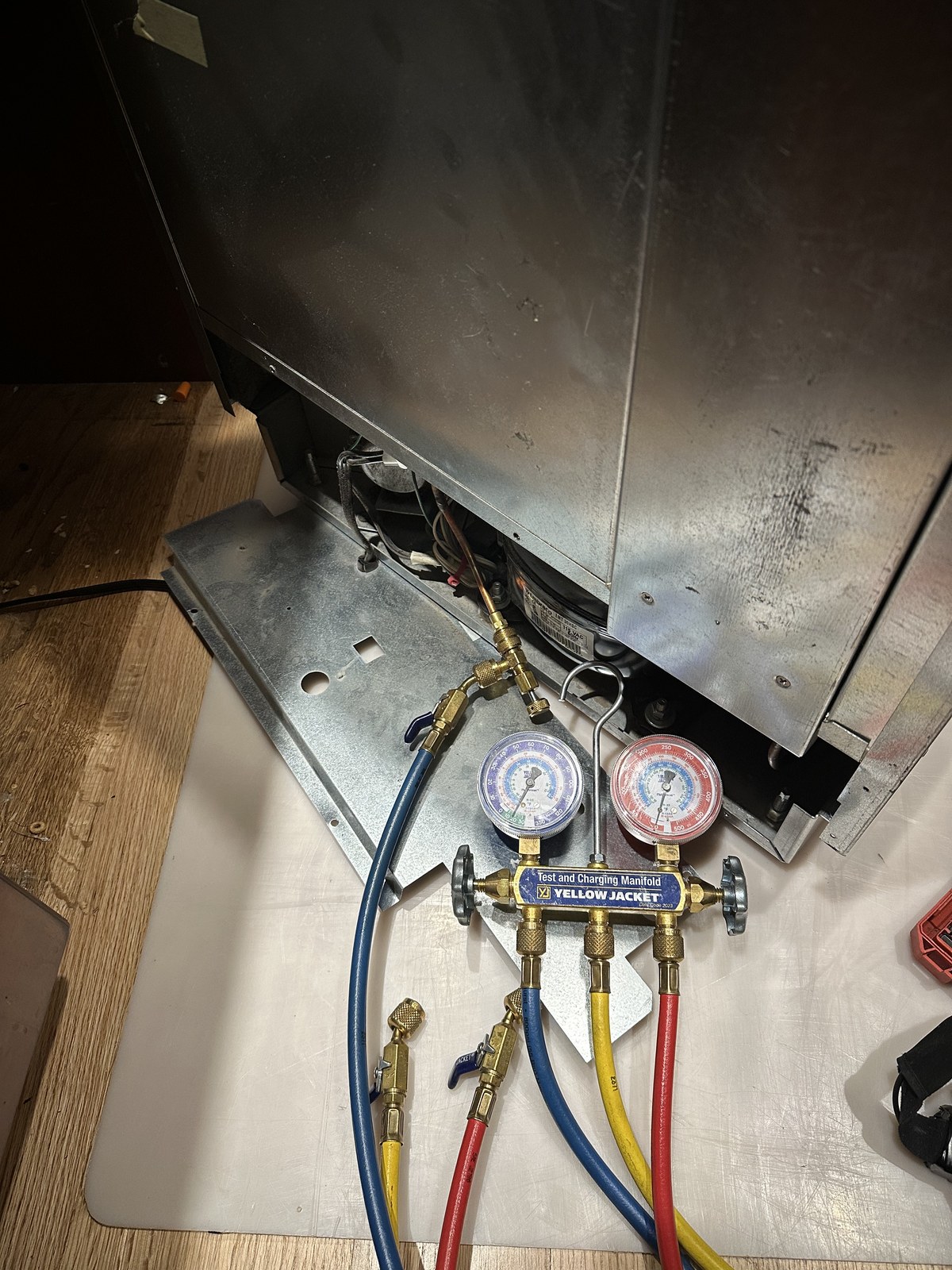 Sub-Zero 424G wine cooler compressor compartment with refrigerant gauges connected for a sealed-system pressure test