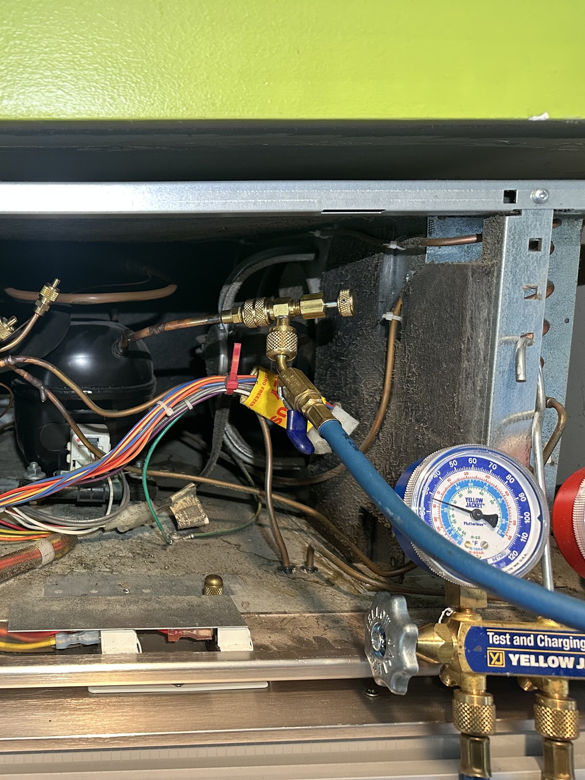 Sub-Zero 650 compressor compartment with refrigerant gauges connected for a sealed-system pressure check