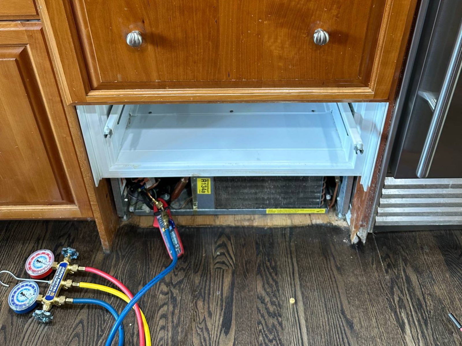 Refrigeration gauge manifold connected to the Sub-Zero freezer's machine compartment below the cabinetry-matched drawer fronts