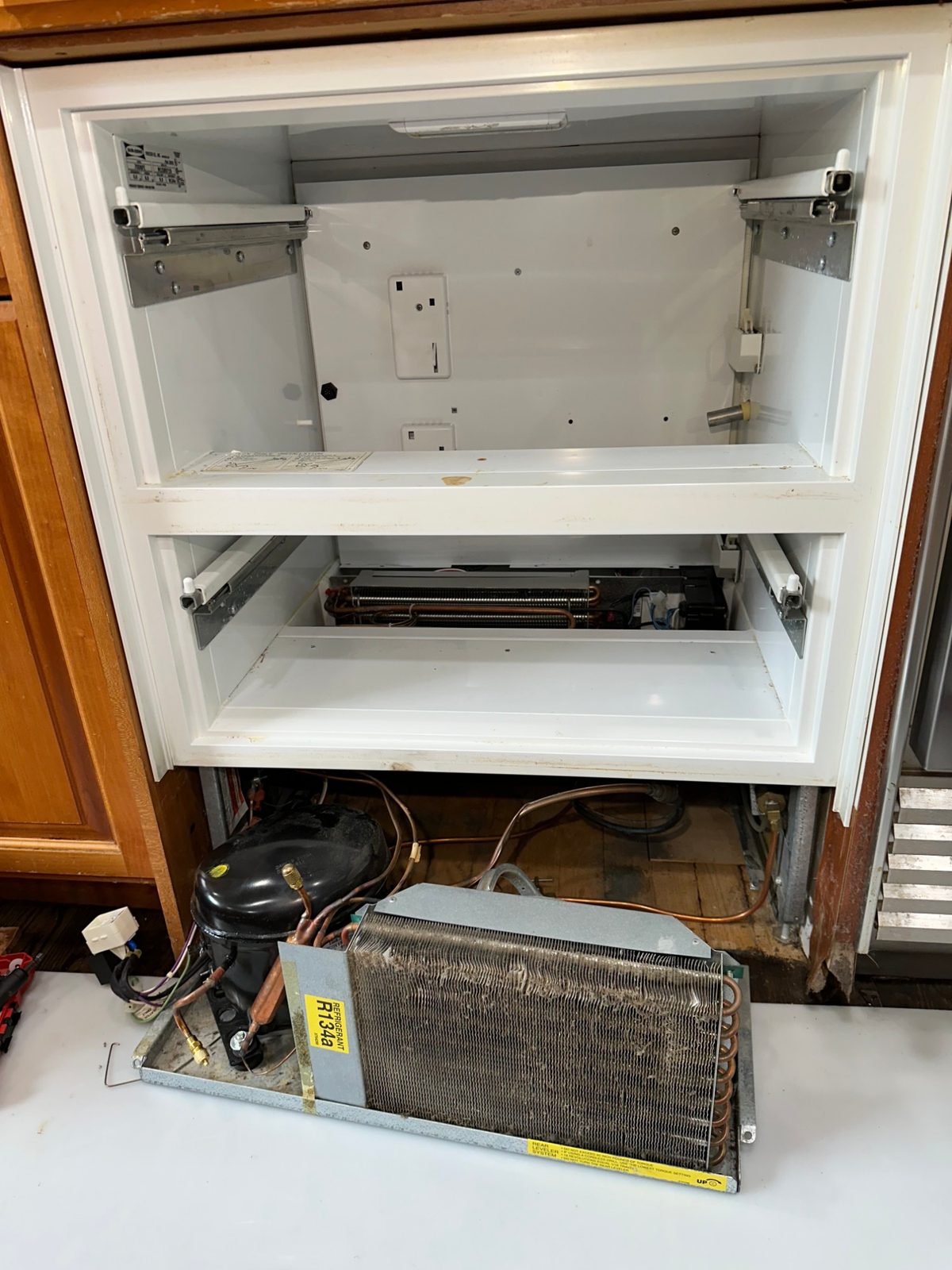 Sub-Zero 700BFI with drawers removed and the compressor and condenser tray pulled out from under the cabinetry