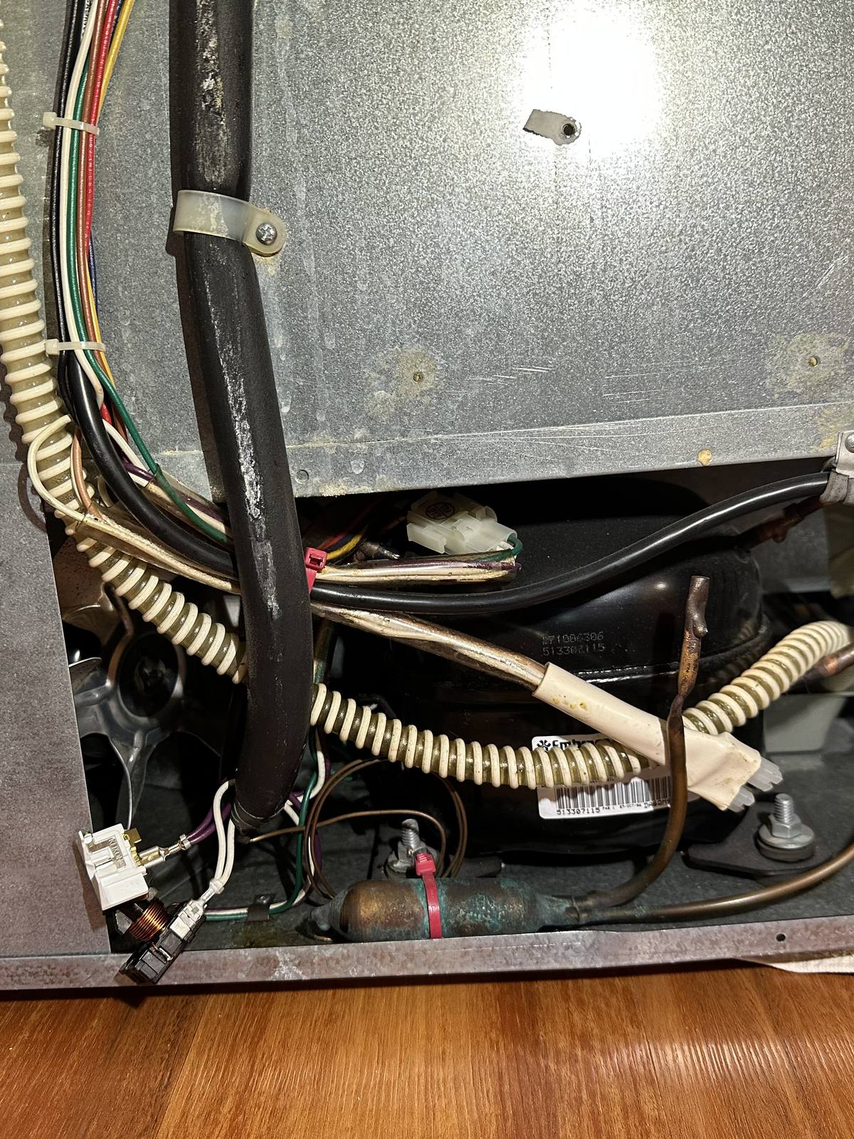 Compressor compartment of the Sub-Zero freezer opened for access, with compressor and wiring exposed