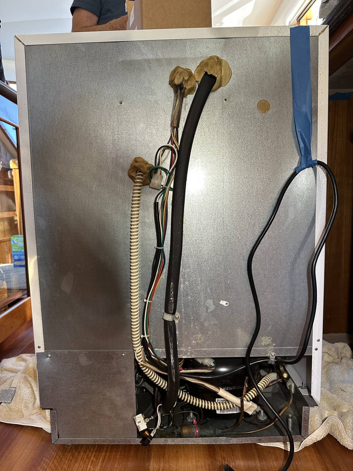 Sub-Zero freezer pulled out of its built-in cabinetry on the yacht, back panel and wiring exposed