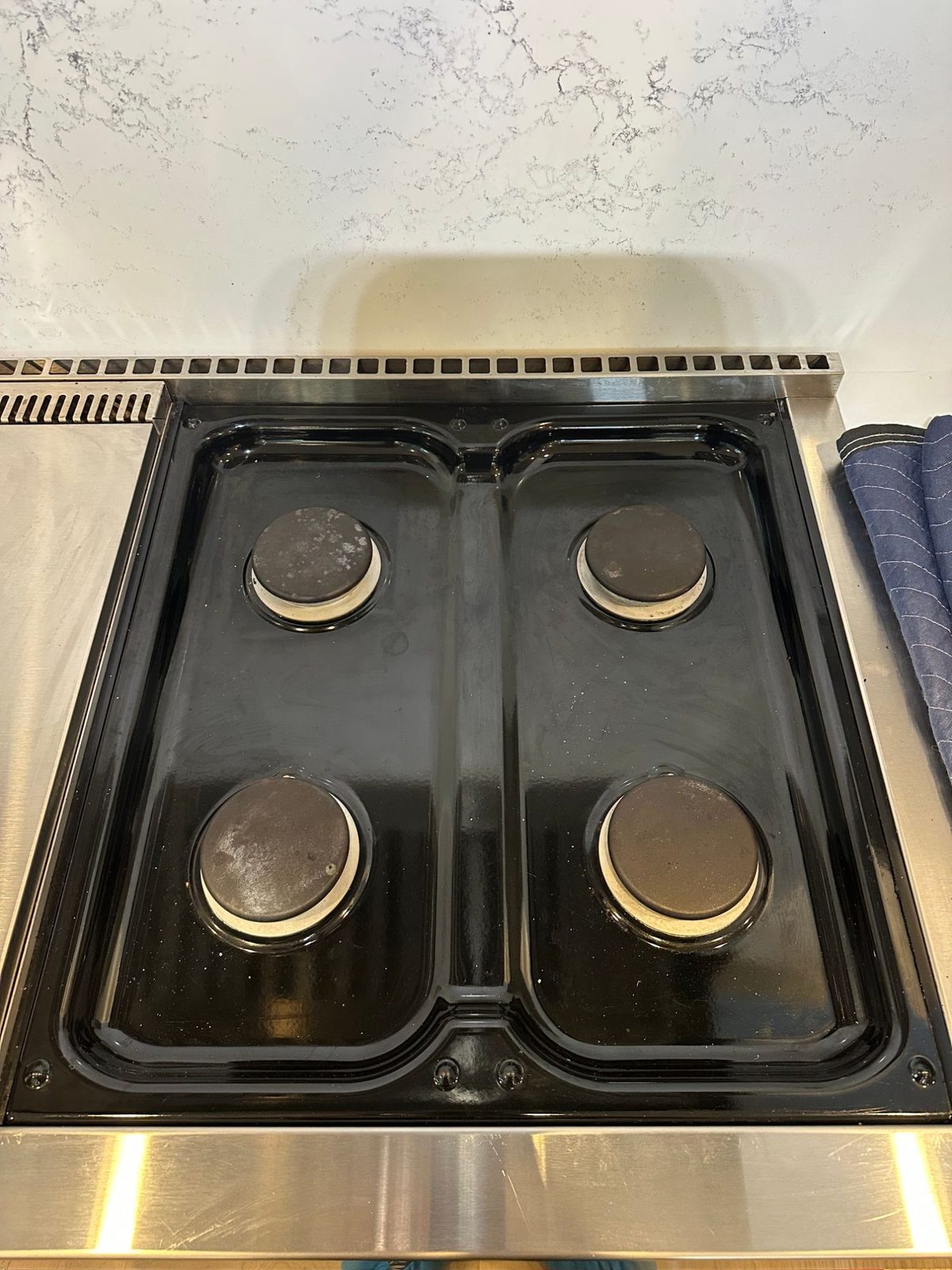 Wolf range burner pan back in place with the four burner caps cleaned and re-seated