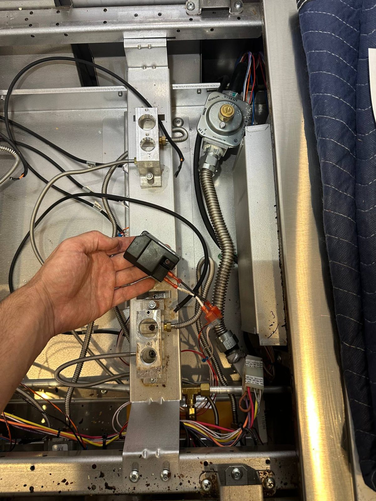 New genuine Wolf spark module being fitted inside the range, next to the burner bases and gas pressure regulator