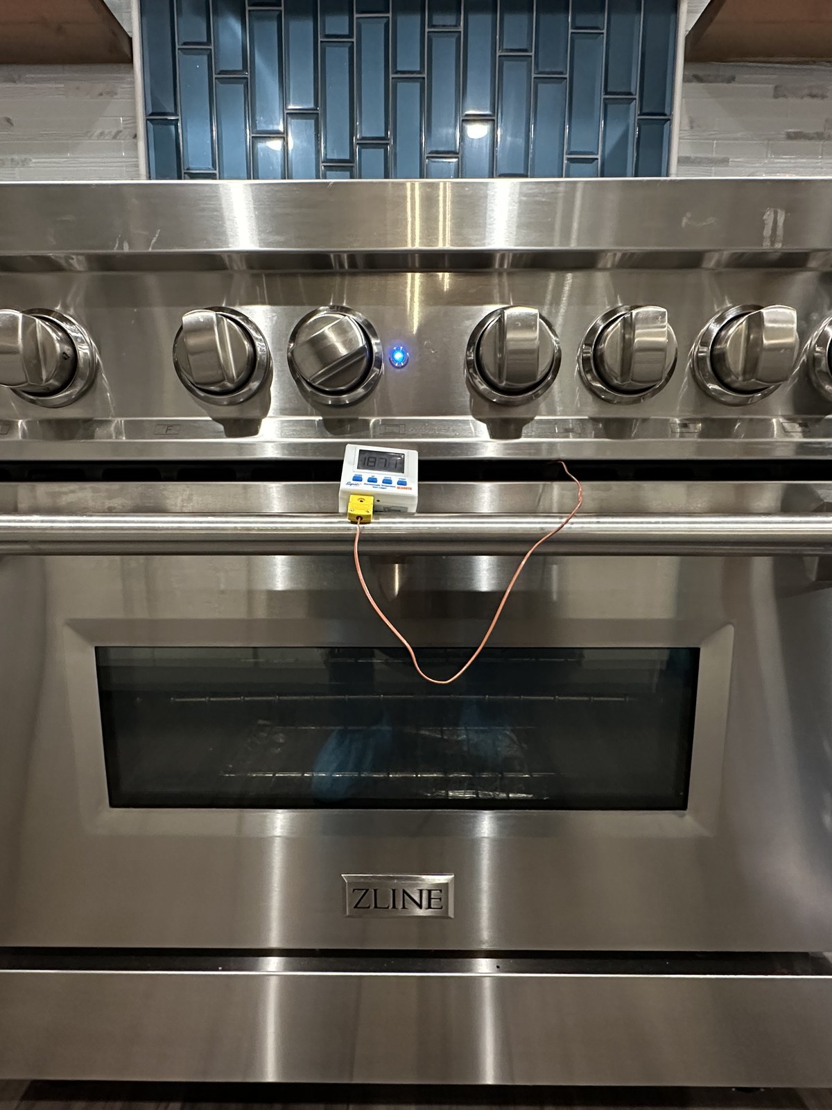 ZLINE range with a digital probe thermometer clipped to the door during oven temperature calibration
